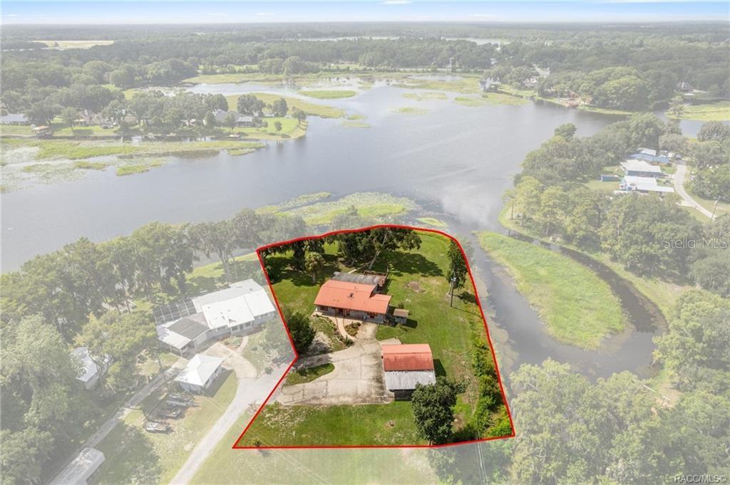 An aerial view shows a house and detached garage on a waterfront lot — 8004 E HALCYON ISLE COURT, INVERNESS, FL