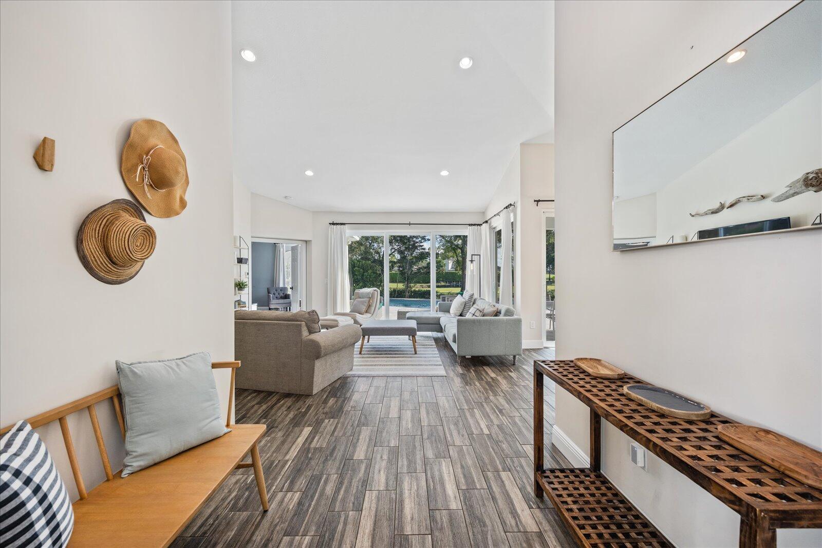 A bright living room features wood-look tile floors, a neutral sofa, and a rear patio view — 2466 Muir Circle, Wellington FL 33414, WELLINGTON, FL