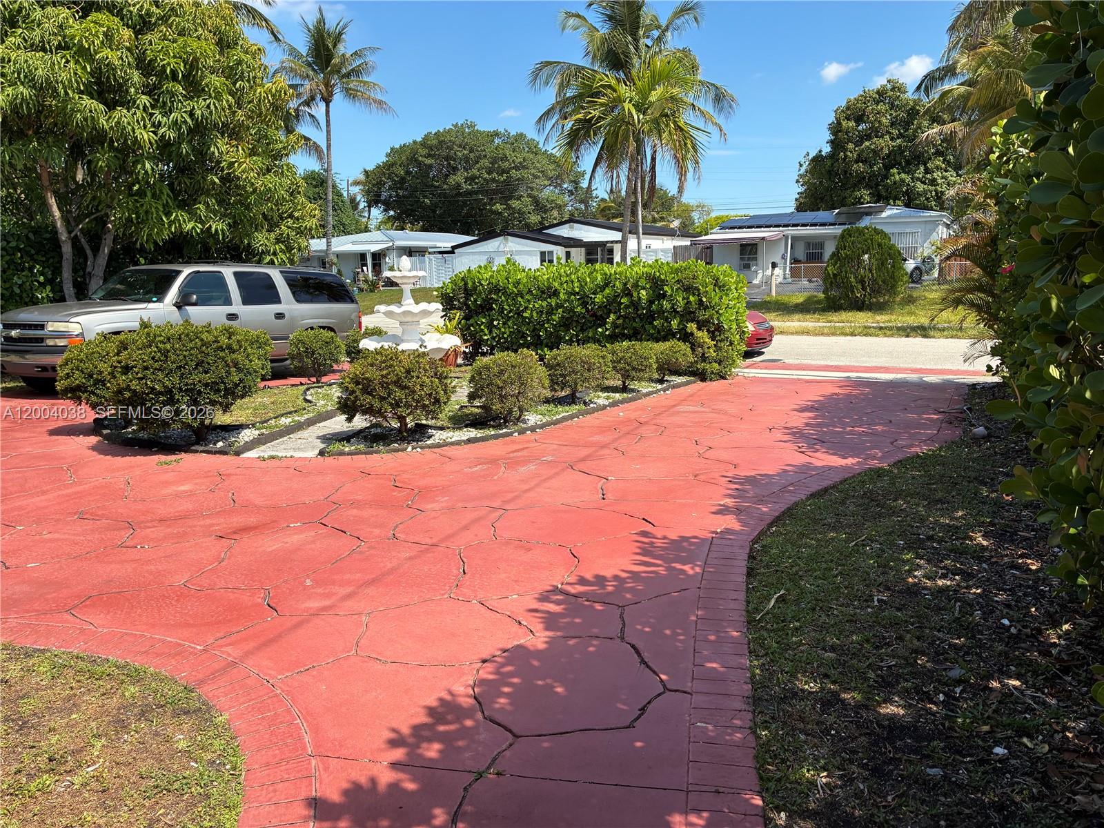 A bedroom features a wooden dresser, a bed with green bedding, and tiled flooring — 1440 NE 174th St, North Miami Beach FL 33162, NORTH MIAMI BEACH, FL