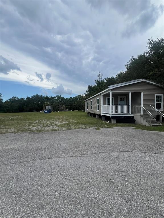 A single-story manufactured home with a front porch sits next to a large open field — 10916 N NEBRASKA AVENUE, TAMPA, FL