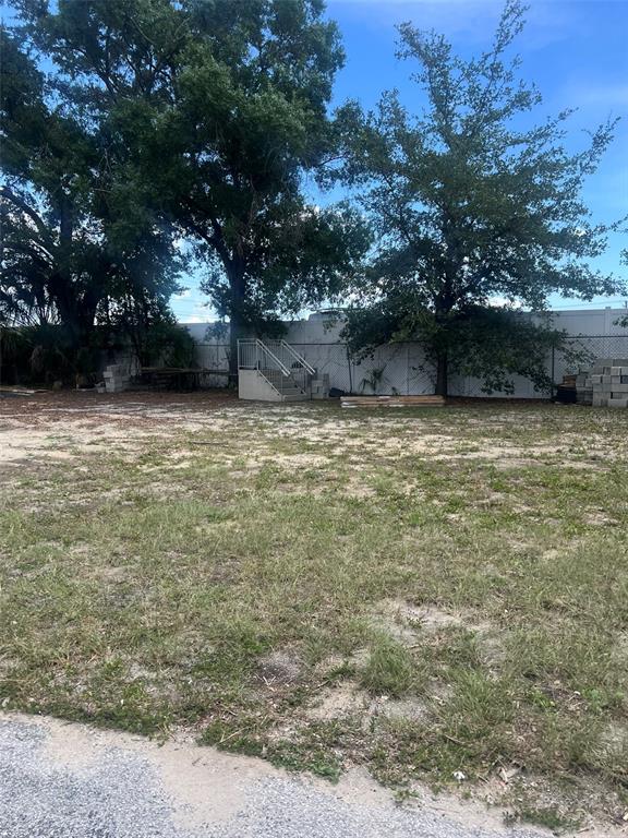 A vacant, grassy lot features mature trees, a small concrete staircase, and a white fence — 10916 N NEBRASKA AVENUE, TAMPA, FL