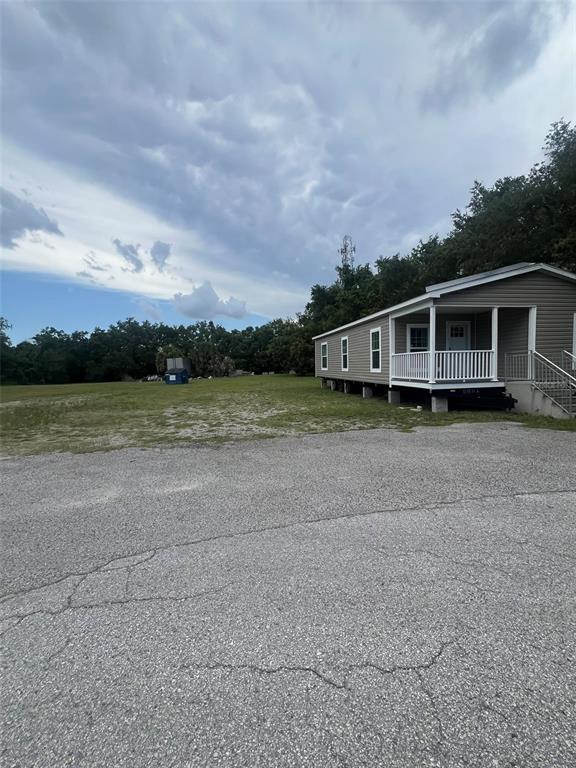 A manufactured home with a front porch sits on a large, open gravel lot — 10916 N NEBRASKA AVENUE, TAMPA, FL