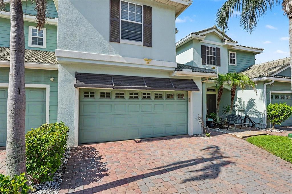 A two-story house with a light green exterior, a two-car garage, and a brick driveway — 1380 ISABELLA DRIVE UNIT 105, MELBOURNE, FL