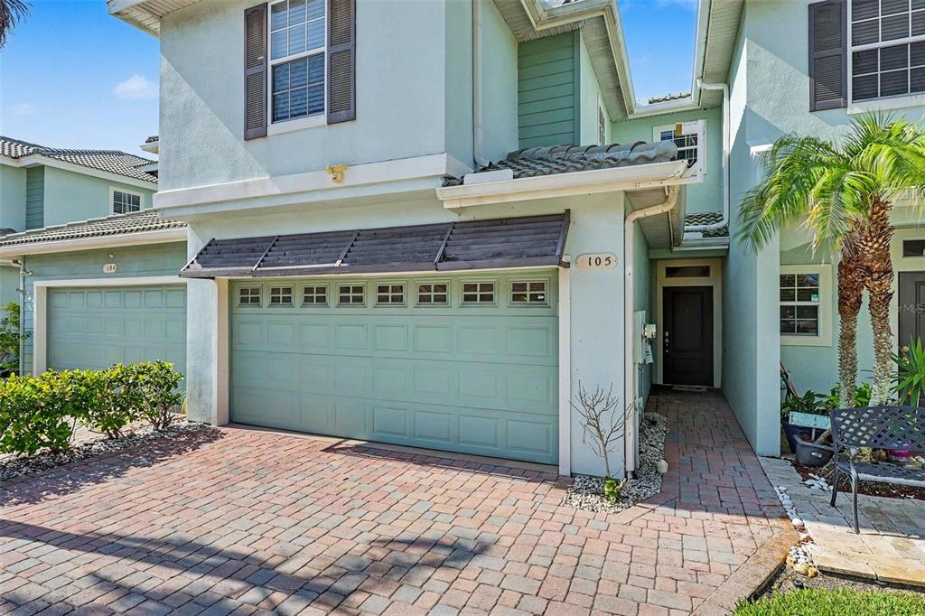 A two-story light blue townhouse with a brick driveway, a garage, and a front entrance — 1380 ISABELLA DRIVE UNIT 105, MELBOURNE, FL