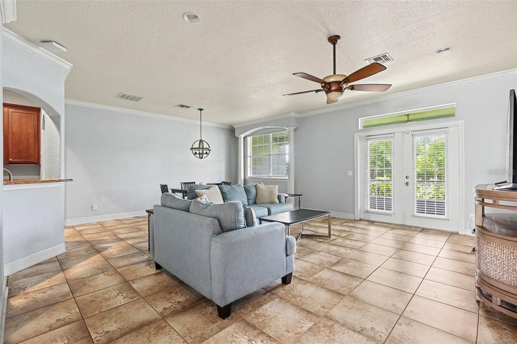 A living room with tile flooring, a blue sectional sofa, and a ceiling fan — 1380 ISABELLA DRIVE UNIT 105, MELBOURNE, FL