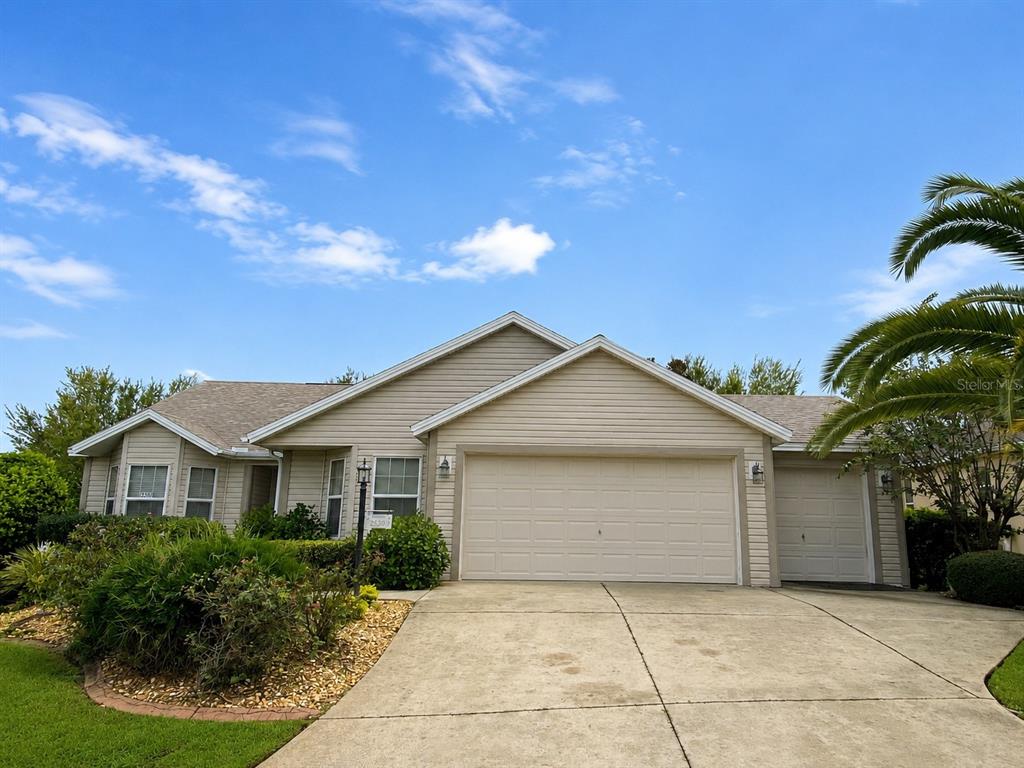 A single-story house with beige siding, a two-car garage, and a concrete driveway — 2530 SAFFRON LANE, THE VILLAGES, FL