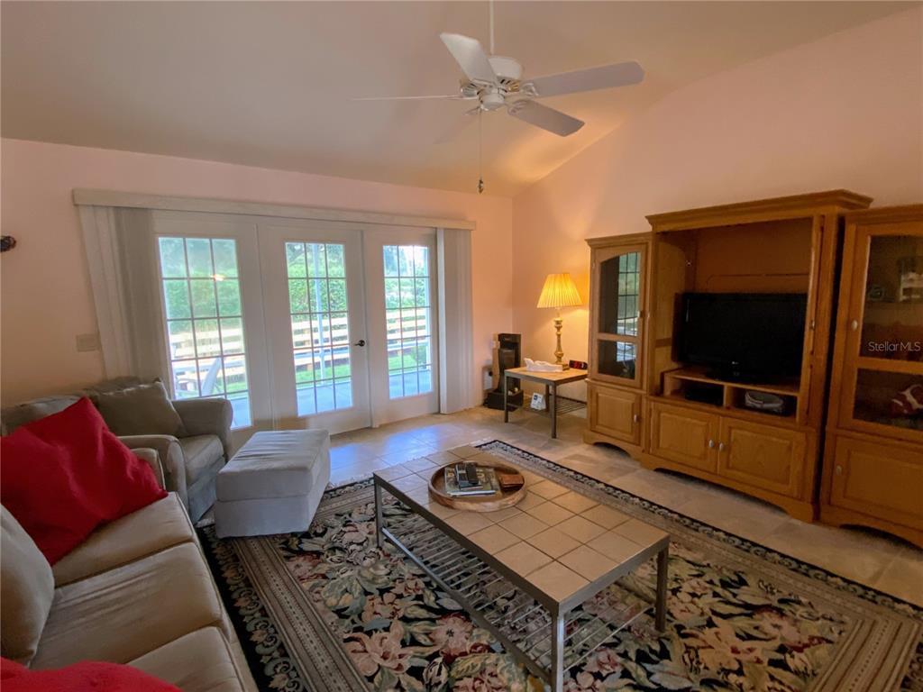 A living room features a tiled floor, a patterned area rug, and a wooden entertainment center — 2530 SAFFRON LANE, THE VILLAGES, FL