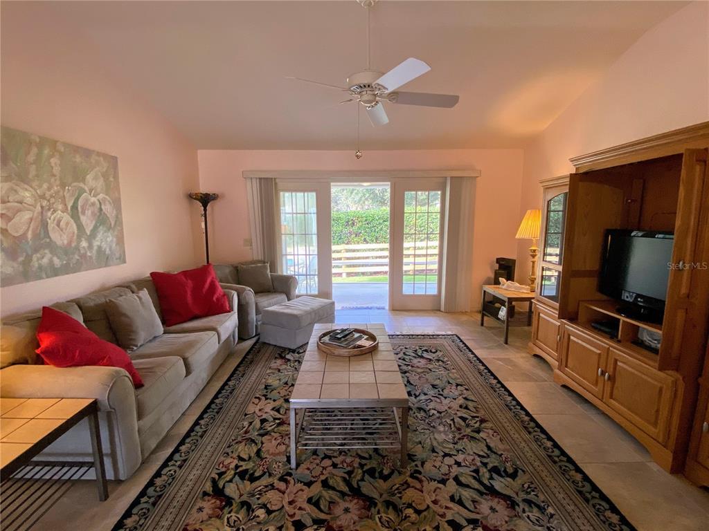 A living room features a beige sofa, a patterned rug, and glass doors leading outside — 2530 SAFFRON LANE, THE VILLAGES, FL