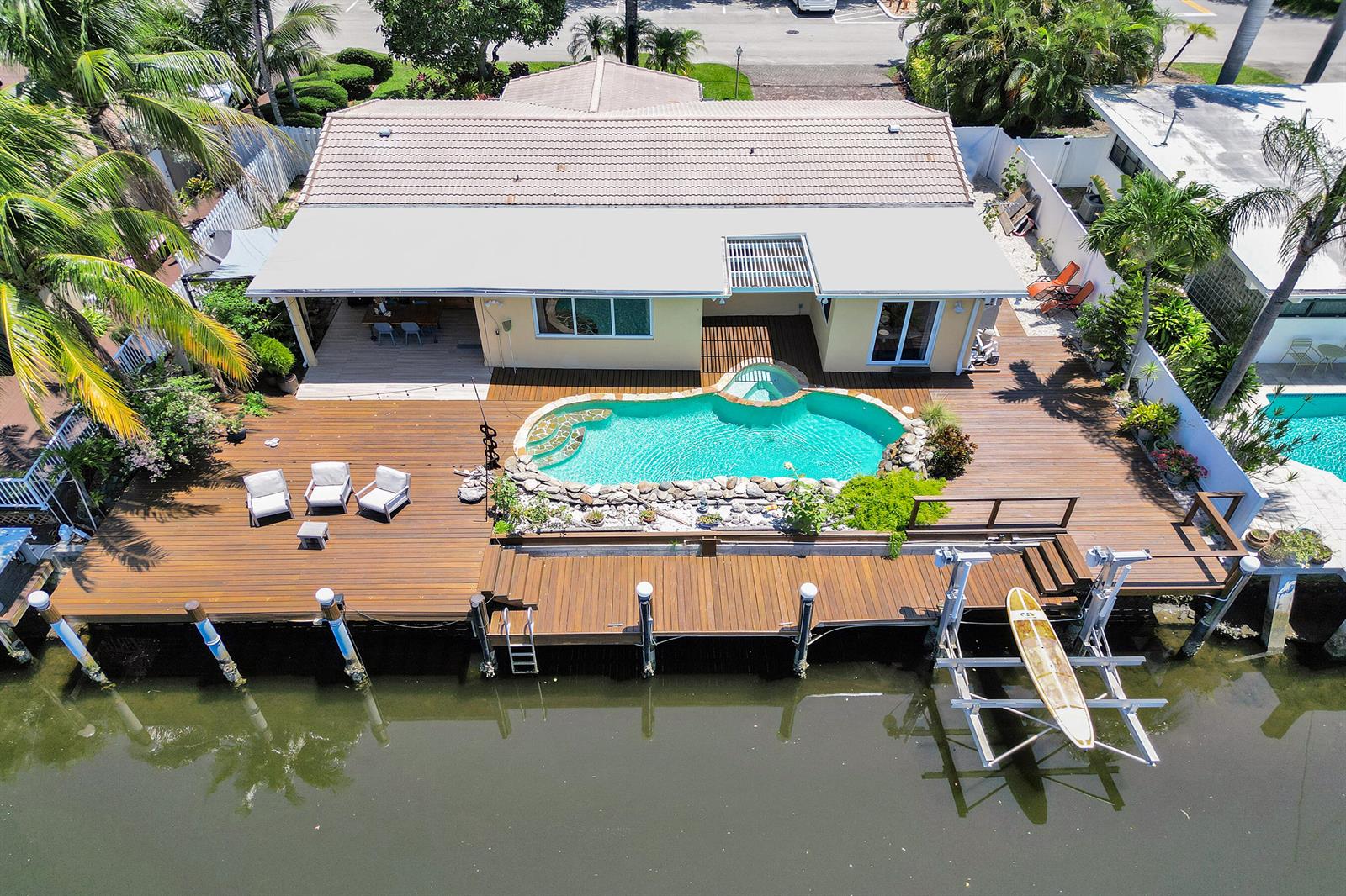 An aerial view of a waterfront house with a wooden deck, pool, and boat lift — 2265 SE 12th Street, Pompano Beach FL 33062, POMPANO BEACH, FL