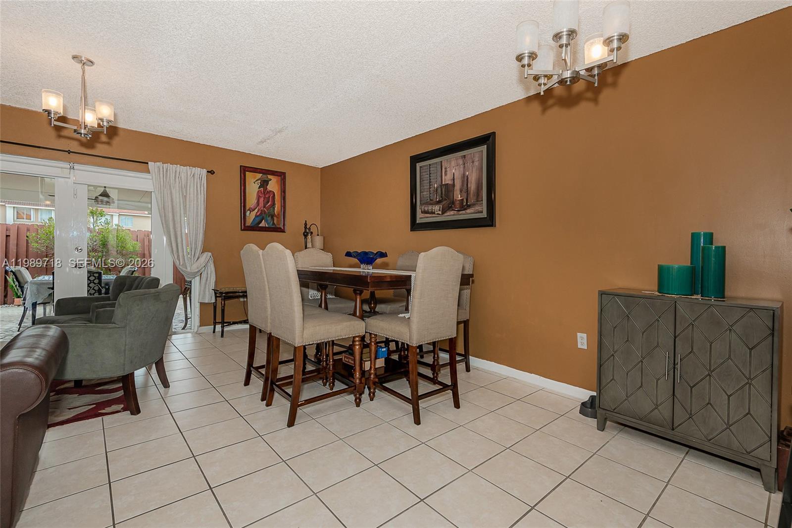 A dining room with a wooden table, upholstered chairs, brown walls, and tiled flooring — 17757 SW 141st Ct, Miami FL 33177, MIAMI, FL