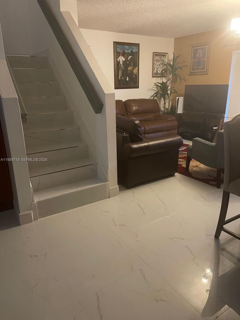 A living room features white marble-look tile flooring, a staircase, and brown leather furniture — 17757 SW 141st Ct, Miami FL 33177, MIAMI, FL