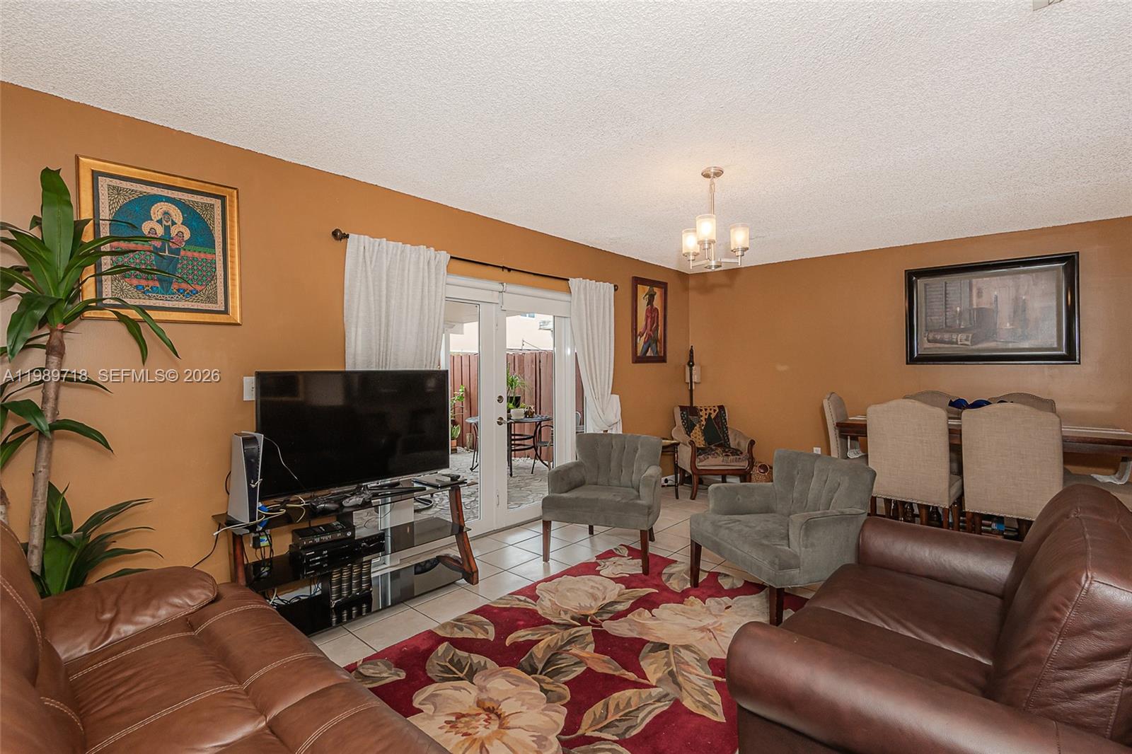 A living room with brown walls, a floral rug, leather sofas, and a glass television stand — 17757 SW 141st Ct, Miami FL 33177, MIAMI, FL