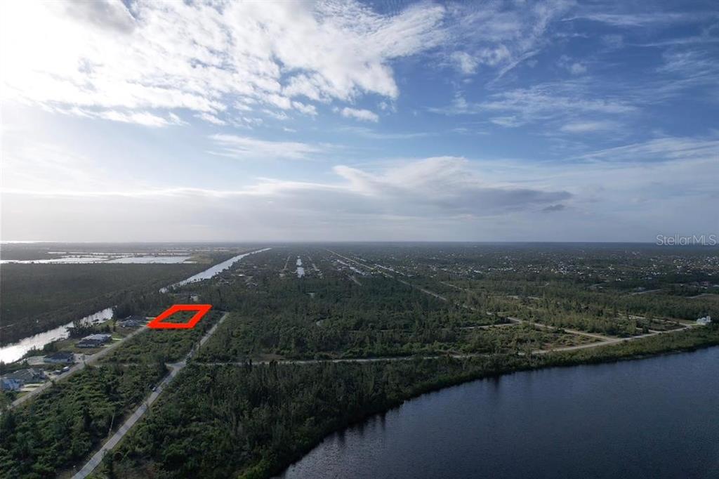 An aerial view shows a rectangular plot of land highlighted in red near a canal — 16733 LIGGETT CIRCLE, PORT CHARLOTTE, FL