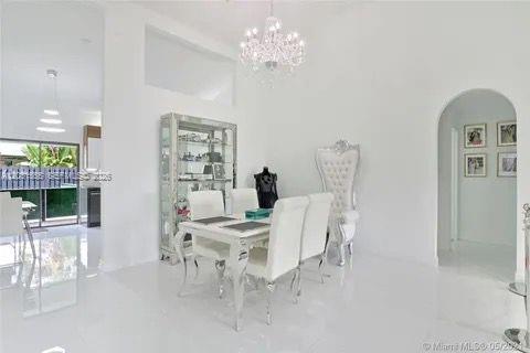 A bright dining room features white tile floors, a glass display cabinet, and a chandelier — 270 SE 7th St, Dania Beach FL 33004, DANIA BEACH, FL