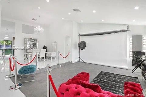 A bright, white studio space features a red velvet sofa, stanchions, and photography lighting equipment — 270 SE 7th St, Dania Beach FL 33004, DANIA BEACH, FL