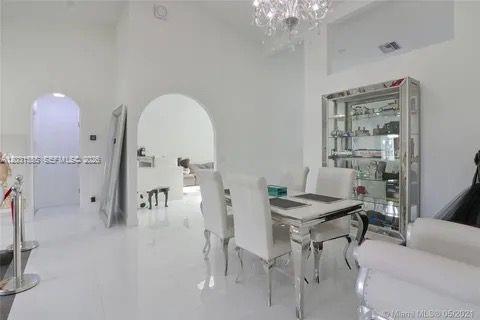A bright dining room with white tile floors, a glass display cabinet, and arched doorways — 270 SE 7th St, Dania Beach FL 33004, DANIA BEACH, FL