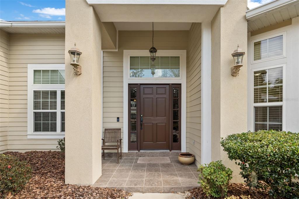The exterior entrance features a brown front door, a tiled porch, and beige siding — 3495 SW 73RD WAY, GAINESVILLE, FL