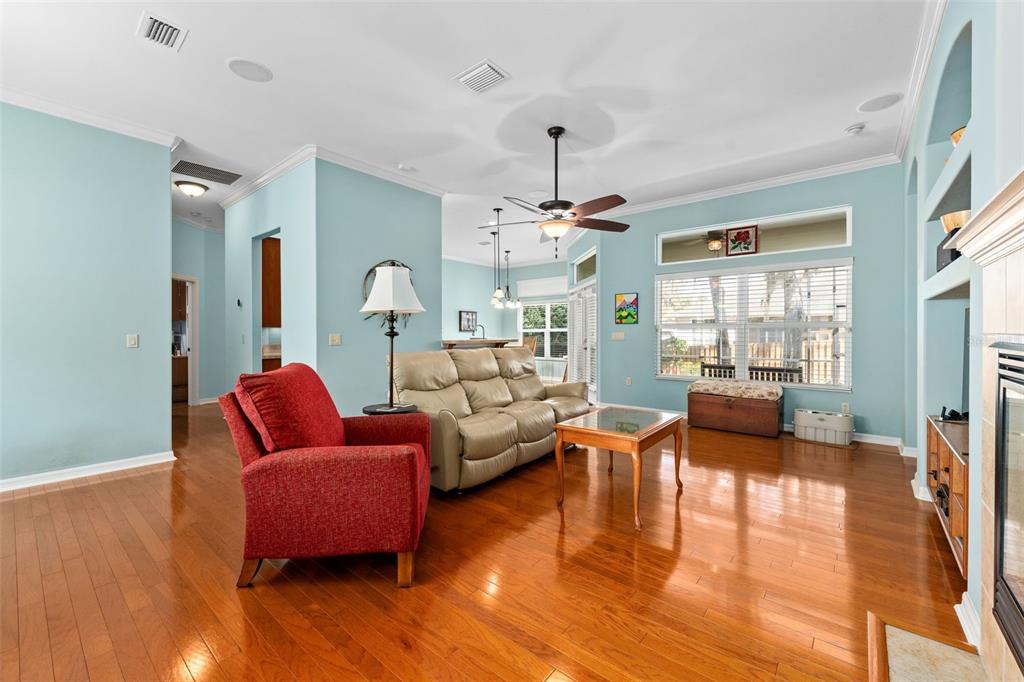 A living room features light blue walls, hardwood floors, a red armchair, and a leather sofa — 3495 SW 73RD WAY, GAINESVILLE, FL