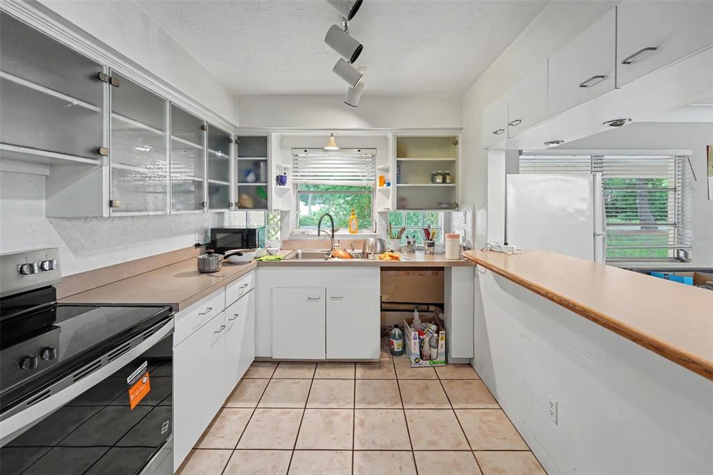 A kitchen features white cabinets, a tile floor, a breakfast bar, and a stainless stove — 6415 2ND AVENUE N, ST PETERSBURG, FL