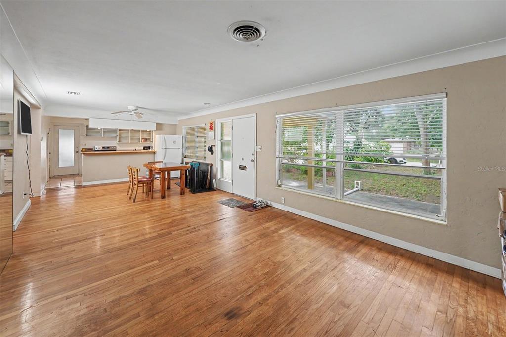 An open-concept living and dining area features hardwood floors, a kitchen counter, and large windows — 6415 2ND AVENUE N, ST PETERSBURG, FL