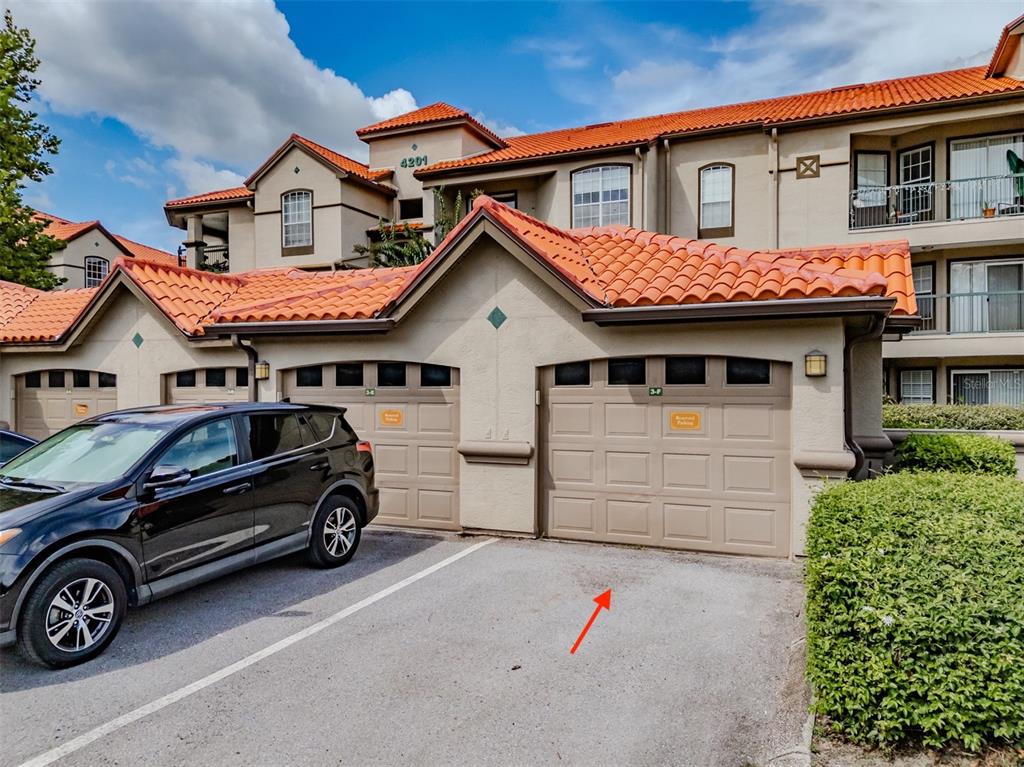 A black SUV is parked in front of a tan garage with a red tile roof — 4201 WOODSTORKS WALK WAY UNIT 3302, LUTZ, FL