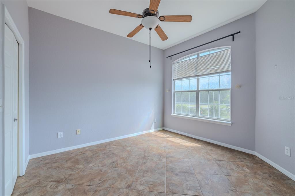 An empty room with light gray walls, tile flooring, a ceiling fan, and a window — 4201 WOODSTORKS WALK WAY UNIT 3302, LUTZ, FL