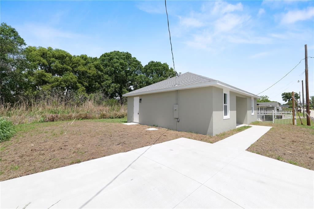 The exterior of a light-colored, single-story house features a concrete driveway and a grassy yard — 3353 S COMBEE ROAD, LAKELAND, FL