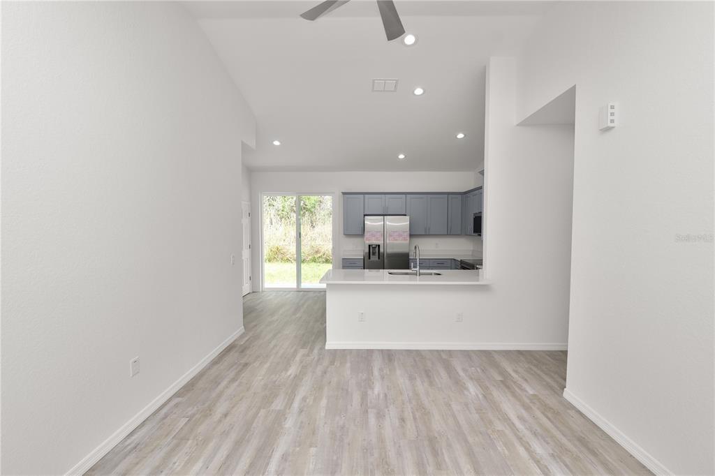 A kitchen with gray cabinets and a breakfast bar overlooks a living area with sliding doors — 3353 S COMBEE ROAD, LAKELAND, FL