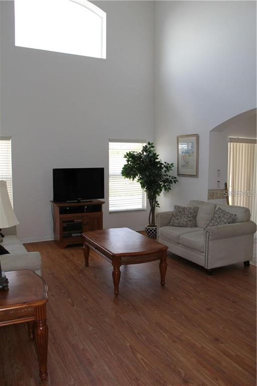 A living room features high ceilings, wood-look flooring, a television console, and a beige sofa — 806 SOLANA CIRCLE, DAVENPORT, FL