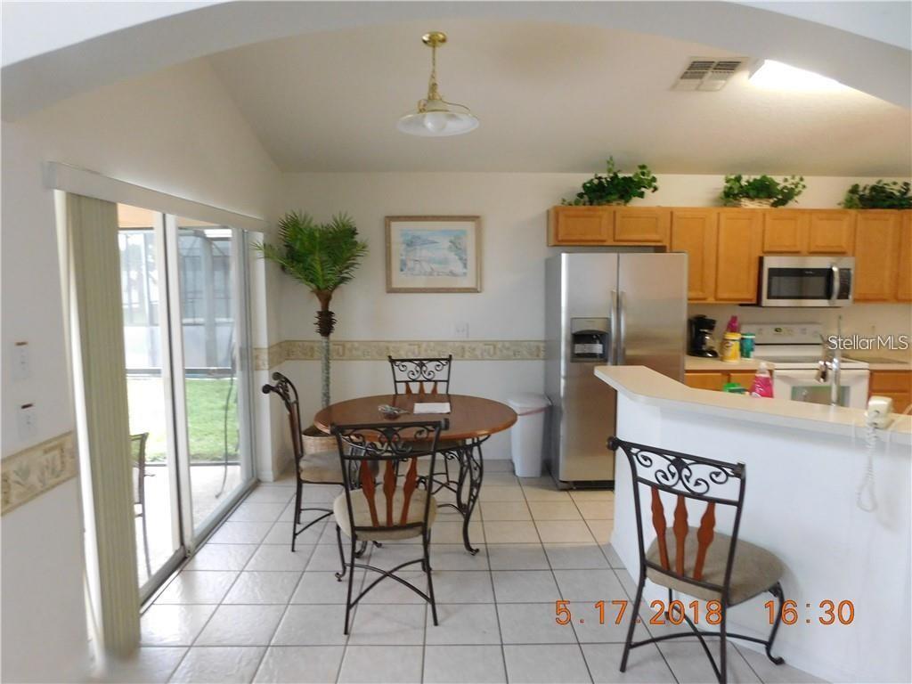 A kitchen and dining area features tile flooring, wood cabinets, and a sliding glass door — 806 SOLANA CIRCLE, DAVENPORT, FL