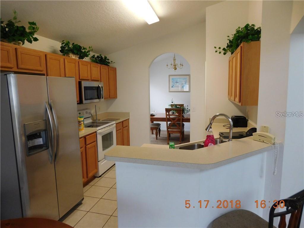 A kitchen with light wood cabinets, stainless steel appliances, and a breakfast bar counter — 806 SOLANA CIRCLE, DAVENPORT, FL