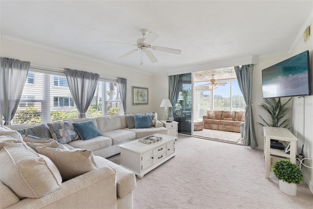 A living room features a large sectional sofa, a white coffee table, and sliding glass doors — 426 BOUCHELLE DRIVE UNIT 101, NEW SMYRNA BEACH, FL