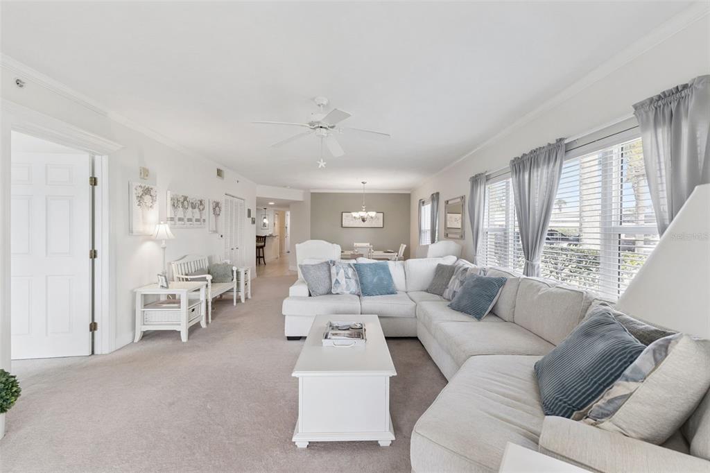 A living room features a white sectional sofa, a coffee table, and light-colored carpeting — 426 BOUCHELLE DRIVE UNIT 101, NEW SMYRNA BEACH, FL