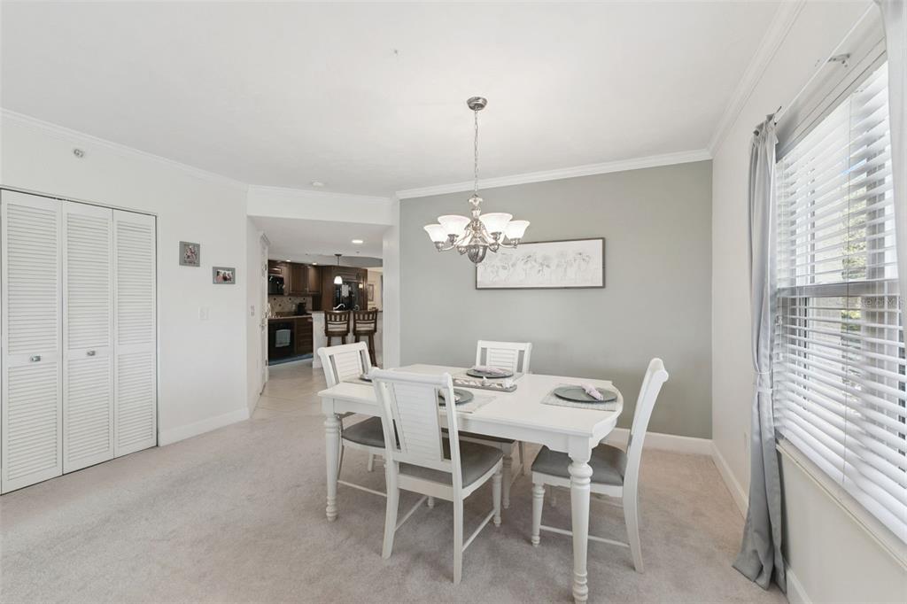 A dining room features a white table with four chairs, a chandelier, and carpeted flooring — 426 BOUCHELLE DRIVE UNIT 101, NEW SMYRNA BEACH, FL