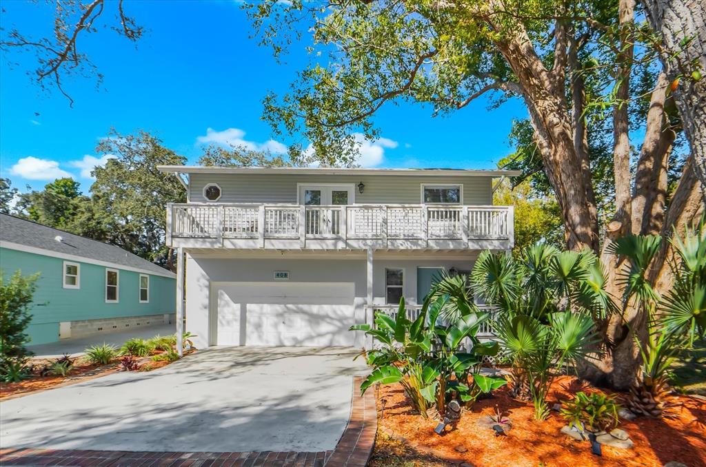 A two-story house with a white garage, a second-floor balcony, and surrounding landscaping — 408 GEORGIA AVENUE, CRYSTAL BEACH, FL