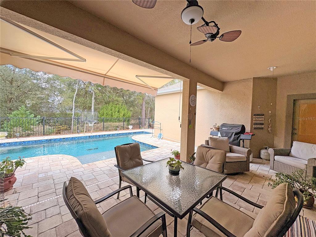 A covered patio features a dining set, lounge chairs, and a view of a swimming pool — 1528 BLUE GRASS BOULEVARD, DELAND, FL