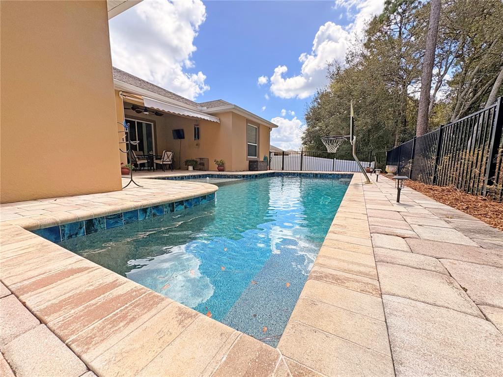 A backyard swimming pool with a paved deck and a basketball hoop sits beside a house — 1528 BLUE GRASS BOULEVARD, DELAND, FL