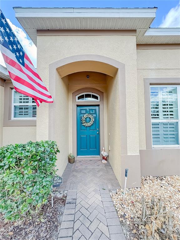 A teal front door with a wreath is centered under an arched entryway — 1528 BLUE GRASS BOULEVARD, DELAND, FL