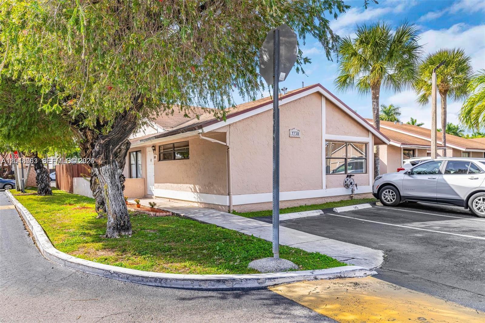 A single-story tan house with a parking space and a large tree in the front — 7730 SW 156th Ct # A145, Miami FL 33193, MIAMI, FL