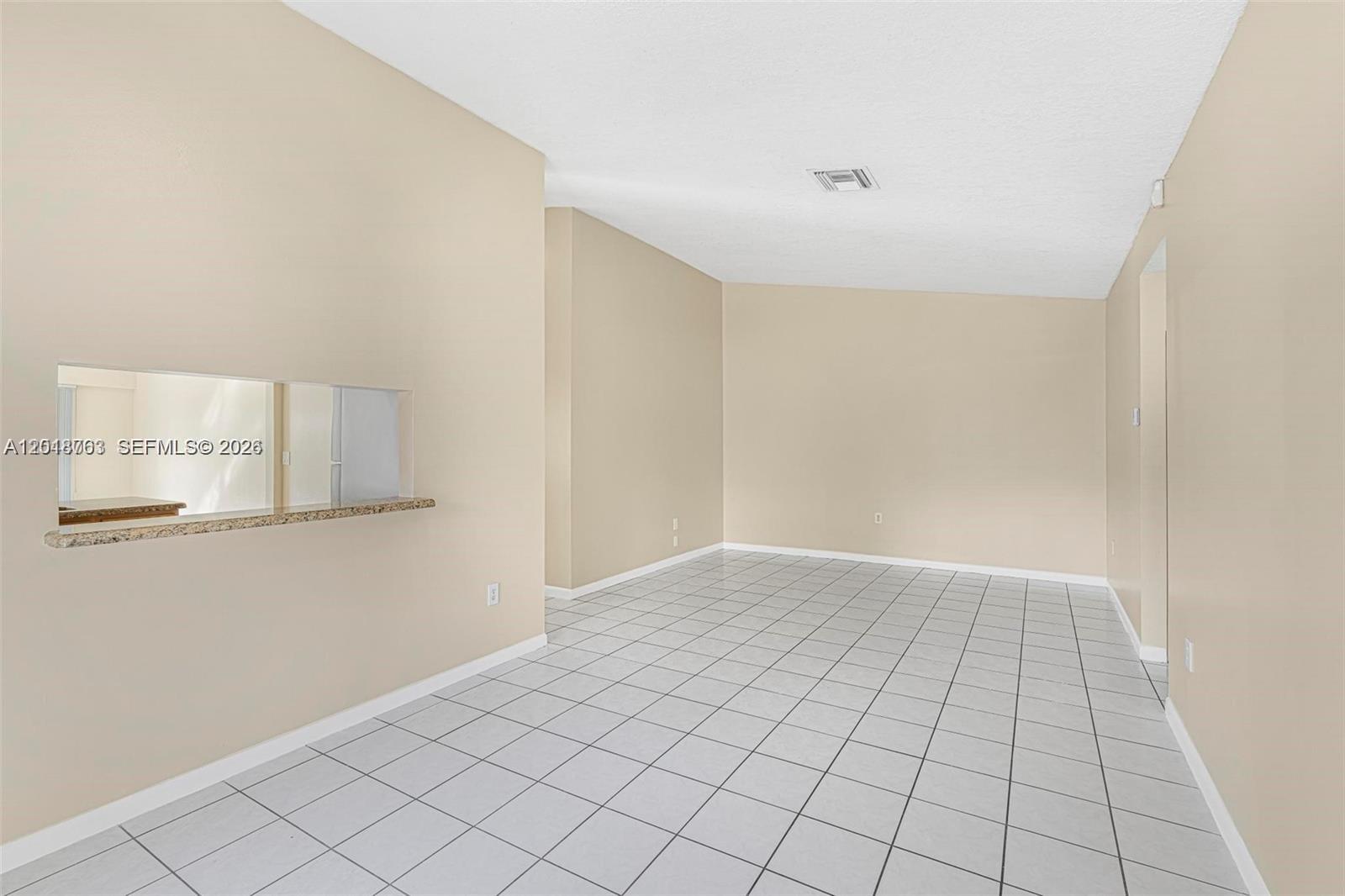 An empty room features beige walls, white tile flooring, and a granite-topped pass-through window — 7730 SW 156th Ct # A145, Miami FL 33193, MIAMI, FL