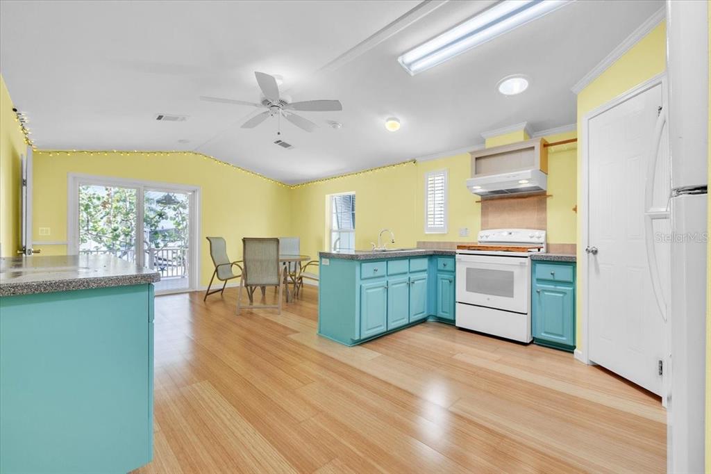 A kitchen and dining area with yellow walls, turquoise cabinets, and light wood flooring — 8320 RIVERSIDE DRIVE UNIT 101, PUNTA GORDA, FL