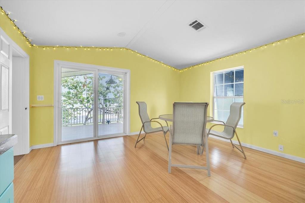 A dining area with yellow walls, light wood flooring, a sliding glass door, and furniture — 8320 RIVERSIDE DRIVE UNIT 101, PUNTA GORDA, FL