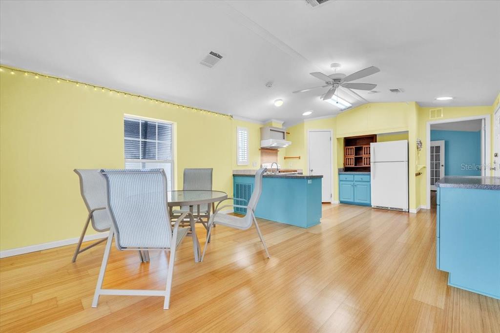 A dining area and kitchen with yellow walls, blue cabinets, and light wood flooring — 8320 RIVERSIDE DRIVE UNIT 101, PUNTA GORDA, FL