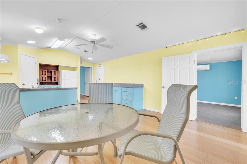 A dining area with a glass table and chairs opens to a kitchen with blue cabinets — 8320 RIVERSIDE DRIVE UNIT 101, PUNTA GORDA, FL