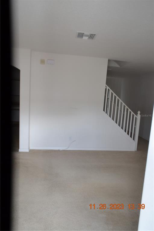 An interior view of a living area featuring beige carpet, white walls, and a staircase — 3343 BROKEN BOW DRIVE, LAND O LAKES, FL