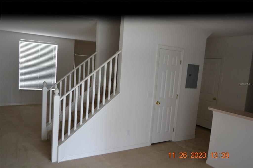 An interior view shows a carpeted room with a staircase, a closed door, and a window — 3343 BROKEN BOW DRIVE, LAND O LAKES, FL