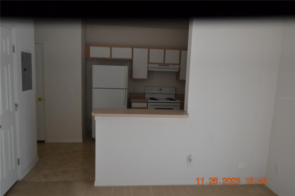 A kitchen with white appliances and cabinets is viewed over a half-wall breakfast bar — 3343 BROKEN BOW DRIVE, LAND O LAKES, FL