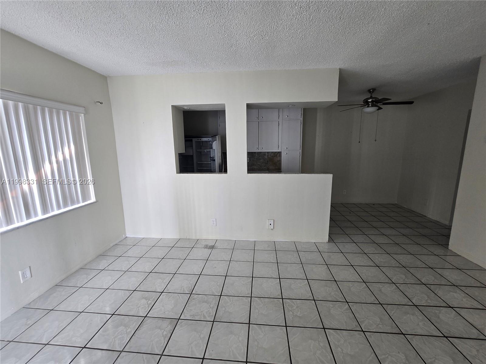 A room with white tile floors, a pass-through window to a kitchen, and a ceiling fan — 2600 S Ocean Dr # S201, Hollywood FL 33019, HOLLYWOOD, FL
