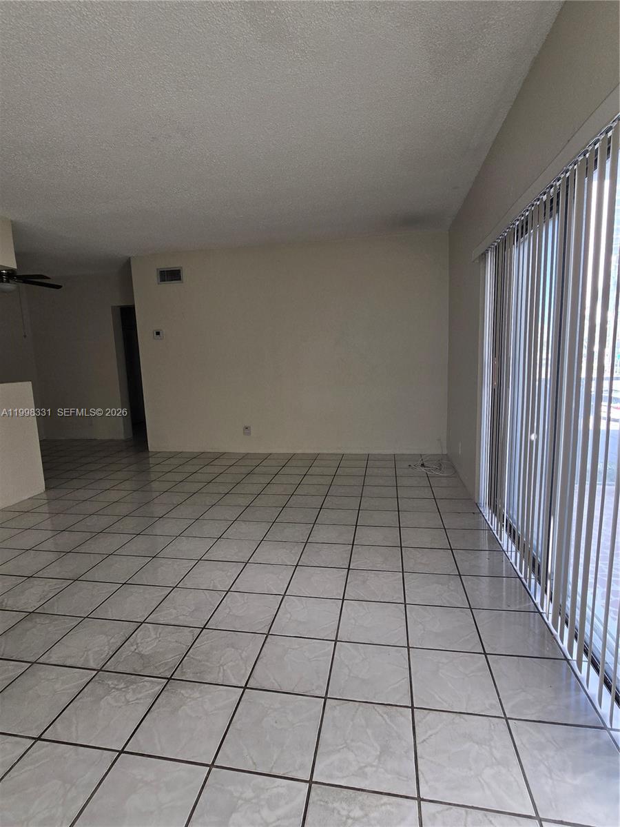 An empty living area features white tiled floors and vertical blinds covering a sliding door — 2600 S Ocean Dr # S201, Hollywood FL 33019, HOLLYWOOD, FL