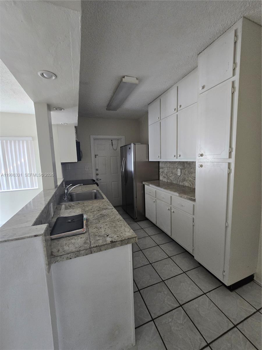 A kitchen features white cabinets, granite countertops, stainless steel appliances, and light-colored tile flooring — 2600 S Ocean Dr # S201, Hollywood FL 33019, HOLLYWOOD, FL